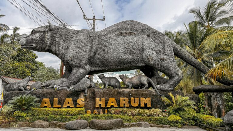 Large stone sculpture of animals at Alas Harum, Bali, surrounded by lush greenery.