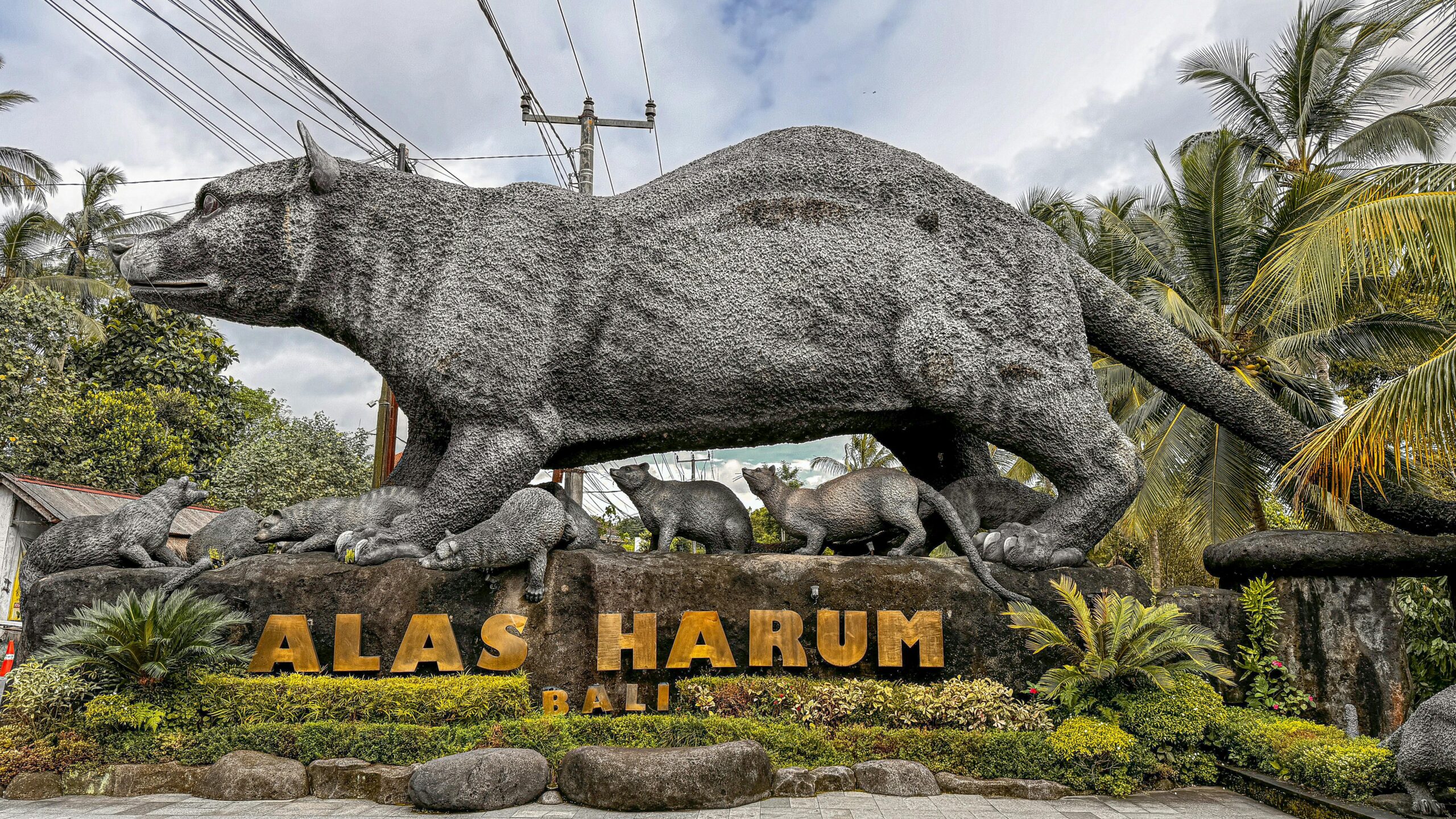 Large stone sculpture of animals at Alas Harum, Bali, surrounded by lush greenery.