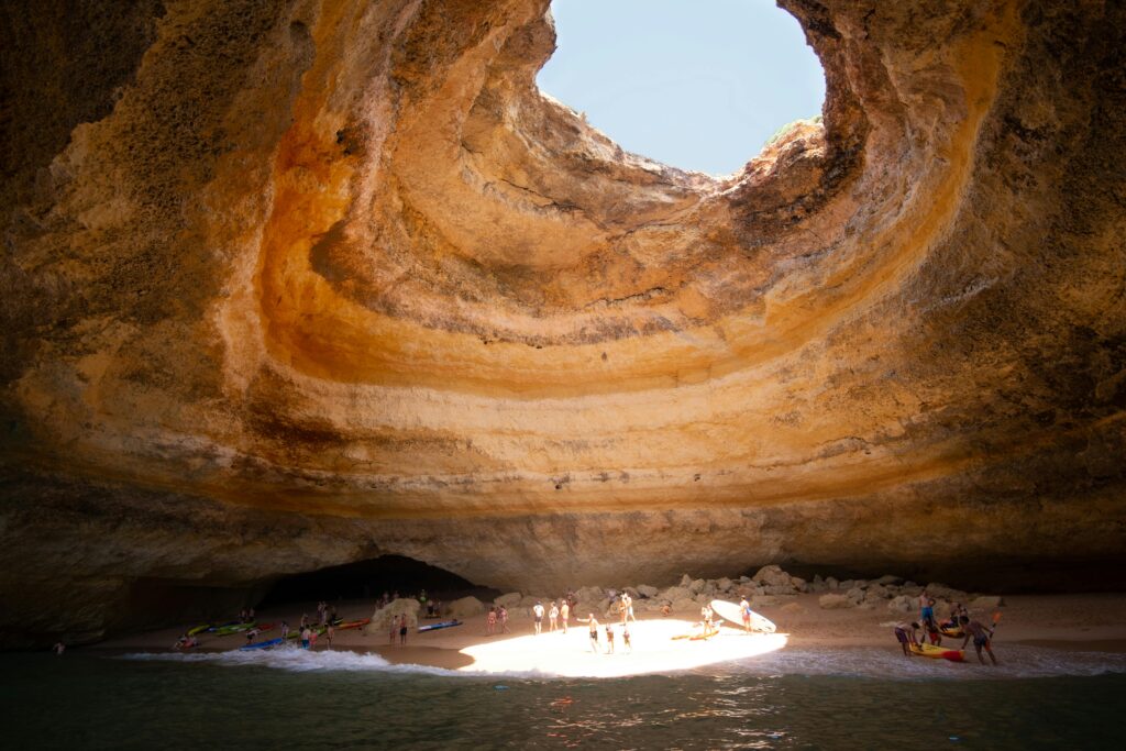 Stunning view of the Benagil sea cave with sunlight illuminating the sandy beach.