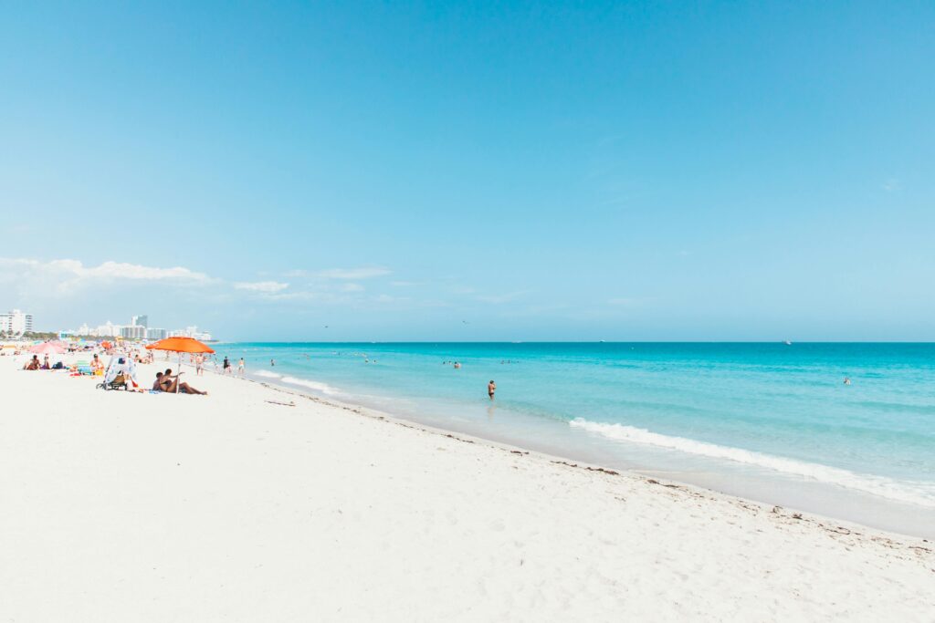 A vibrant Miami Beach scene with clear skies, blue ocean, and white sand.