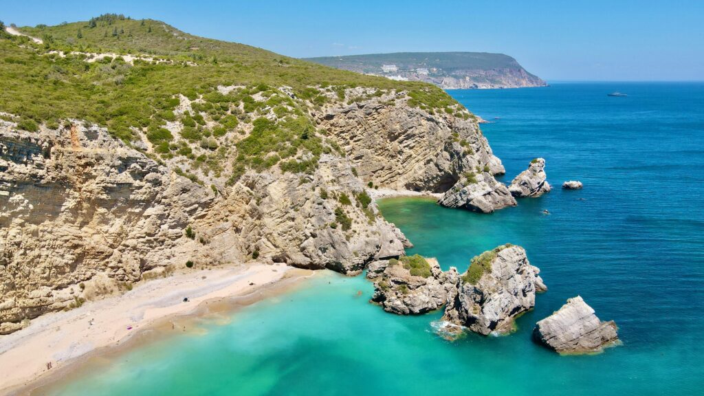 Breathtaking aerial view of Praia do Ribeiro do Cavalo’s rocky coastline and turquoise waters in Portugal.