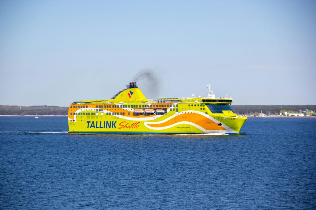 Bright yellow Tallink ferry sailing in blue Baltic Sea under clear sky, near shore.